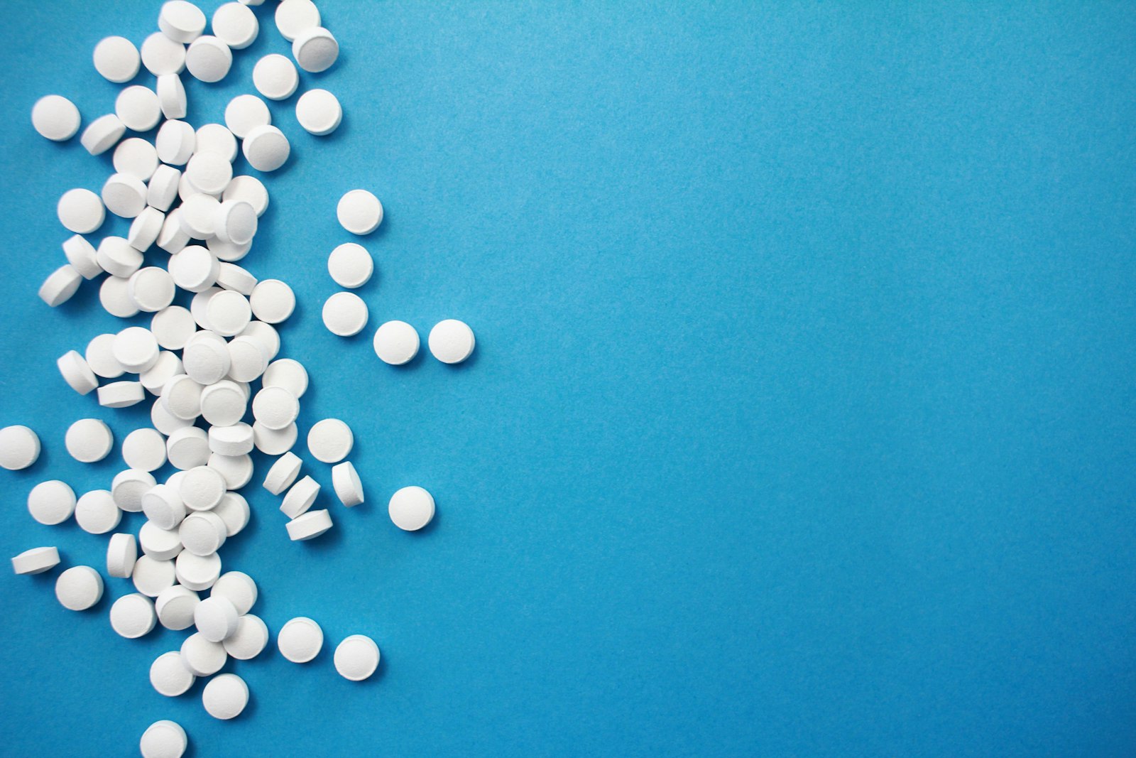 A pile of round white tablets on a blue background